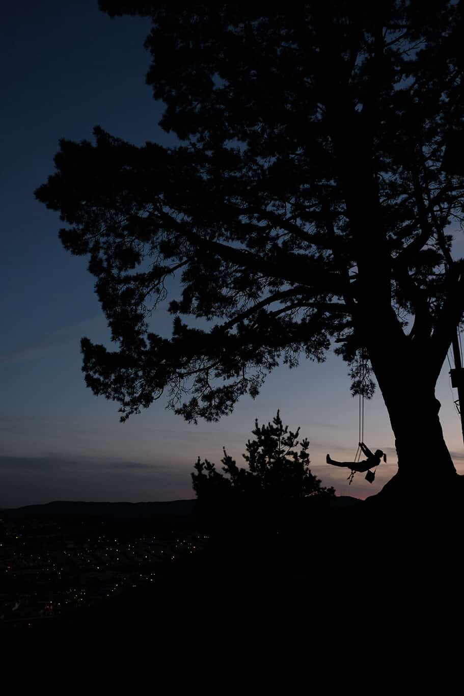 A woman on a swing with a sunset sky