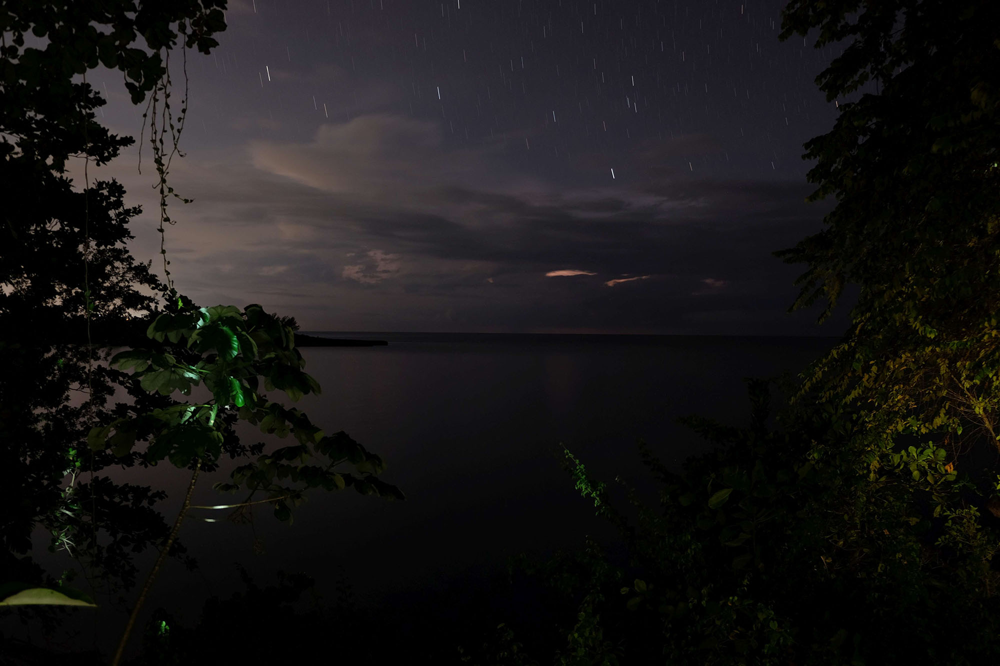 Image of the ocean, startrails, and a thundercloud.